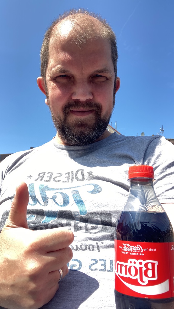 Karsten Dukalskis lächelt mit einer echten Coca-Cola in der Sonne